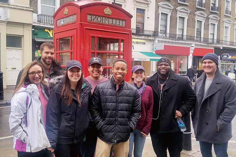 A group of students standing in front of an iconic red phone booth during a trip to London